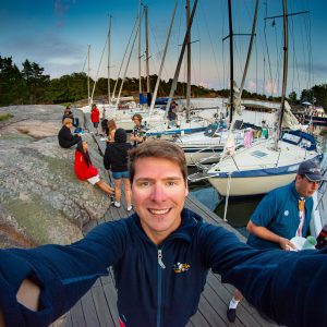Wide lens selfie of myself, Björn Larsson, with sailboats moored in the background at Lökholmen, Sandhamn during Sjökort 2021, a squadron sailing with Träkvista Sjöscoutkår.